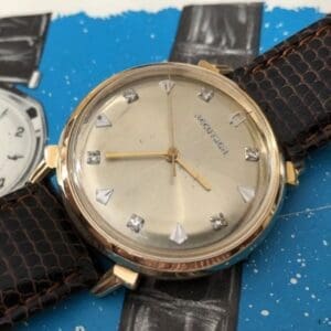 A watch is shown on top of a blue paper.